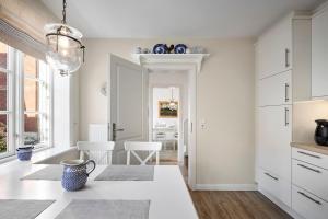 Una cocina con gabinetes blancos y una mesa con un jarrón. en Villa Maiken, en Wyk auf Föhr