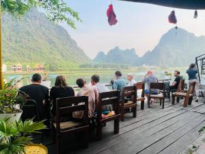 eine Gruppe von Menschen, die an einem Tisch mit Blick auf einen Fluss sitzen in der Unterkunft Phong Nha Coco House in Phong Nha