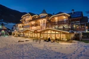 a large building in the snow at night at Renè Dolomites Boutique Hotel in Pozza di Fassa