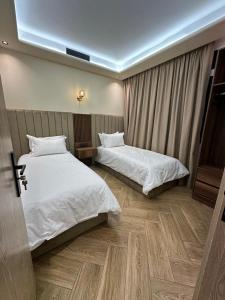 two beds in a hotel room with white sheets at Centrico 8 Tanger Bendiban in Tangier