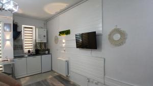 a kitchen with white walls and a tv on a wall at Sfanta Agnes self check in in Popeşti-Leordeni