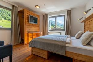 a bedroom with a large bed and a television at Heimat Natur Resort in Prägraten