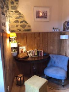 ein Zimmer mit einem blauen Stuhl und einem Tisch mit Büchern in der Unterkunft La Modestine in Le Monastier sur Gazeille