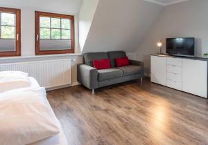 a bedroom with a couch and a chair and a television at Alt Westerland Hüs in Westerland (Sylt)