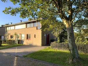 una casa con un árbol al lado de una valla en Wijk de Brabander 117, en Cadzand