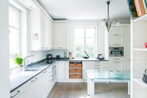 a white kitchen with white cabinets and a glass table at Schloss Suggenstein in Sigmaringen