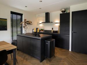 a kitchen with black cabinets and a wooden floor at Beautiful villa on the water in Friesland in Sint Nicolaasga