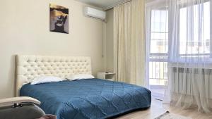 ein Schlafzimmer mit einem blauen Bett und einem großen Fenster in der Unterkunft 1 комнатная драмтеатр 1bedroom apartment in Öskemen