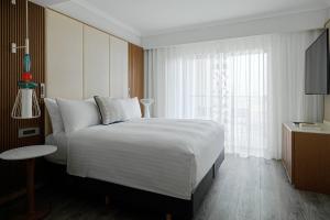 a bedroom with a large white bed and a window at Malta Marriott Resort & Spa in St. Julianʼs