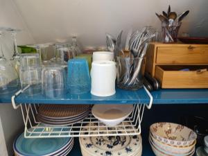 Un estante azul con platos y otros utensilios encima. en Studio au 2e étage de notre maison de ville, en Caen