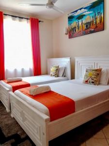 two white beds in a room with red curtains at The Faridooh's Comfy Homes Mtwapa in Mtwapa