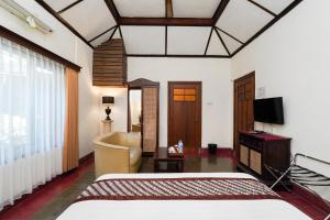 a bedroom with a bed and a living room at Indraloka Heritage Homestay in Yogyakarta