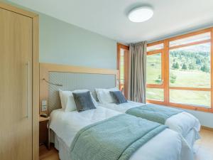 2 bedden in een slaapkamer met een groot raam bij Duplex moderne 3 Chambres - Balcon, Piscine, Spa, Ski aux pieds - FR-1-352-57 in Arc 1800