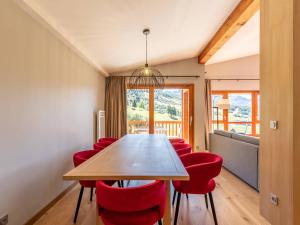 a dining room with a wooden table and red chairs at Duplex 4 chambres avec piscine, spa et parking aux Arcs 1800 - FR-1-352-55 in Arc 1800