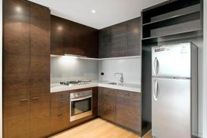 a kitchen with wooden cabinets and a refrigerator at Docklands Private Collection - NEWQUAY in Melbourne