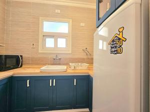 a kitchen with blue cabinets and a sink and a window at Our home Our heaven in Madinaty