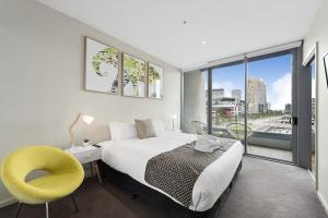 a bedroom with a bed and a chair and a window at Docklands Private Collection - NEWQUAY in Melbourne