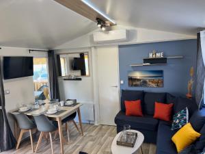 un salon avec un canapé bleu et une table dans l'établissement Mobil Home CasaLuca 3 chambres 2 Salles d'eau, à Canet