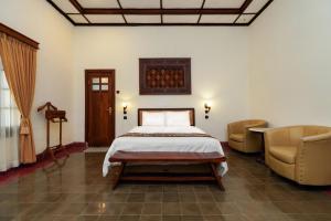 a bedroom with a bed and two chairs at Indraloka Heritage Homestay in Yogyakarta
