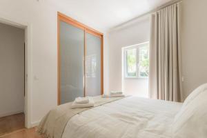 a white bedroom with a large white bed with mirrors at Cascais Center Family Apartment with Courtyard in Cascais