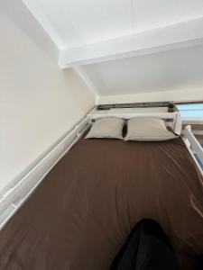 Una cama en una habitación pequeña con paredes blancas. en Joli Studio de 25 M2 proche de Disney, en Collégien