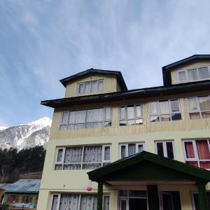 Un gran edificio con una montaña al fondo. en New snow view resort pahalgam, en Pahalgām