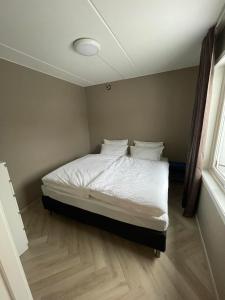 a bedroom with a bed with white sheets and pillows at Ryenstubben in Oslo +4 photos
