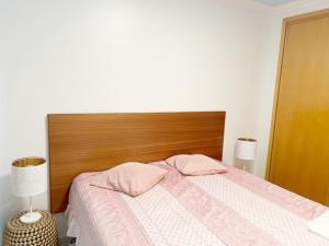 um quarto com uma cama com uma cabeceira de madeira e 2 candeeiros em Varandas Do Sol 2 em Portimão