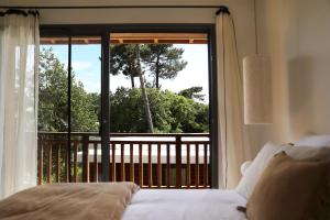 una camera da letto con un letto e vista su un balcone di CLUQUE- Maisons de Vacances a Capbreton Altre 52 foto