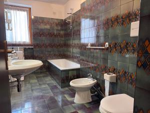 a bathroom with a sink and a toilet and a tub at APPARTAMENTO PANORAMA 016 in Giustino +11 photos