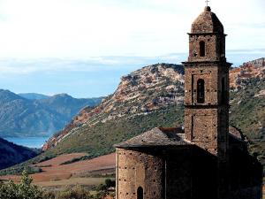 an old church with a mountain in the background at U FARNIENTE in Patrimonio