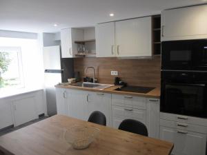 eine Küche mit weißen Schränken und einem Holztisch in der Unterkunft Appartement tout confort 4 personnes à Porté-Puymorens in Porté-Puymorens