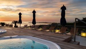 a hot tub on a deck with chairs and umbrellas at Hotel Cristallo in Giulianova