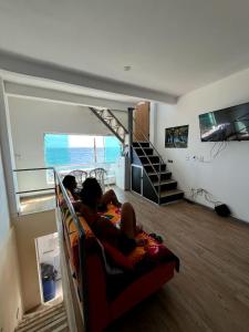 two people sitting on a couch in a living room at Hostel Cantinho do Mar in Salvador +37 photos