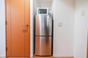 东京Shinjuku luxury Apart ment 2 minutes from Higashi-Shinjuku的不锈钢冰箱,上面配有微波炉