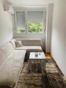 een woonkamer met een bank en een tafel bij Stan na dan Nova Varoš in Banja Luka