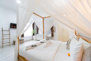 a bedroom with a white bed with a canopy at Villa Putri Mila in Seminyak +40 photos