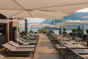 a row of lounge chairs and umbrellas on a deck at Hilton Lake Como in Como