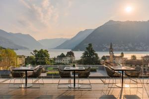 a balcony with tables and chairs and a view of a city at Hilton Lake Como in Como