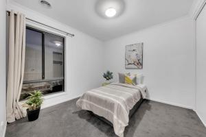 a white bedroom with a bed and a window at Scott House in Truganina