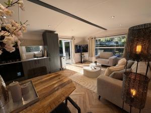 una sala de estar con un sofá y una mesa en VELUWSHOF HOENDERLOO HOLIDAYS Luxe Holidayhomes with PRIVATE JACUZZI'S - SwimmingPool - Tennis Court - Bowling - Supermarket and Children Entertainment, en Hoenderloo