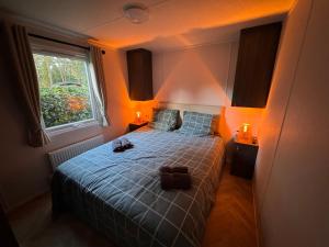 Un dormitorio con una cama con sábanas azules y una ventana. en VELUWSHOF HOENDERLOO HOLIDAYS Luxe Holidayhomes with PRIVATE JACUZZI'S - SwimmingPool - Tennis Court - Bowling - Supermarket and Children Entertainment, en Hoenderloo