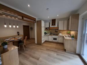 a kitchen with white cabinets and a table and a dining room at Ferienwohnung Heiabett in Wies