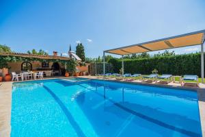 une grande piscine bleue avec des chaises et un pavillon dans l'établissement Villa La Rosaleda - By Dream Villas Pollensa, à El Port