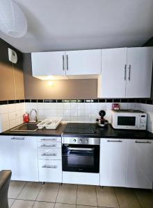 La cuisine est équipée de placards blancs, d'une cuisinière et d'un four micro-ondes. dans l'établissement Bel appartement avec parking privé, à Boussy-Saint-Antoine