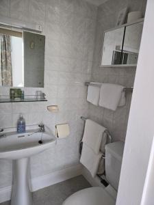 a white bathroom with a sink and a toilet at Shoreline Accommodation in Bournemouth