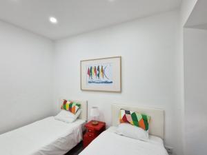 Dos camas en una habitación con paredes blancas. en Marilaura's beach house, en Nazaré