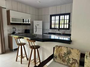 een keuken met een aanrecht en twee barkrukken bij Cantinho da serra in Ubatuba