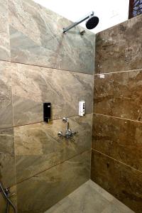 Un baño con ducha con pared de piedra. en Karni Divine Haveli, en Bikaner