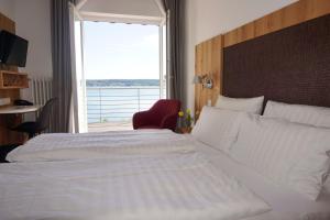 a bedroom with a large bed and a large window at Strandhotel Seehof in Überlingen